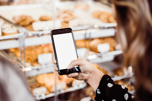 Woman Holding Iphone Mockup In Supermarket